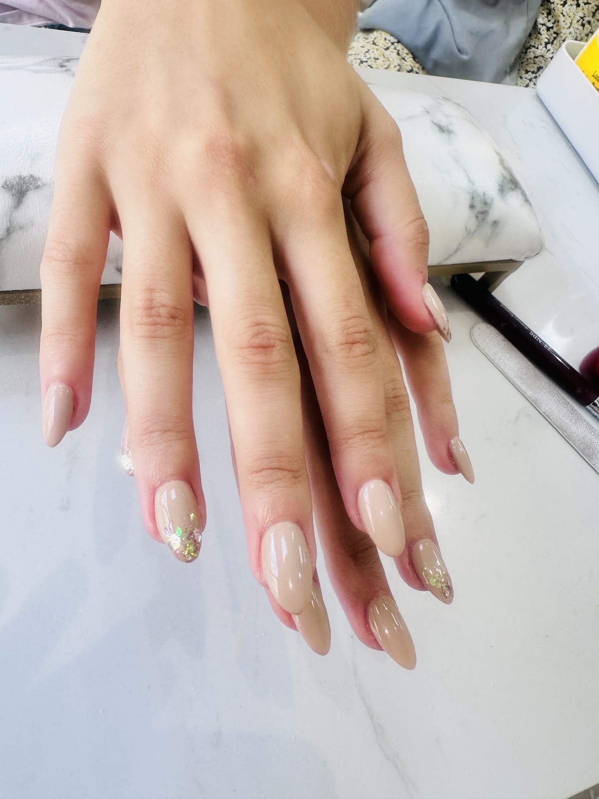 Détail de manucure beige-nude avec paillettes or